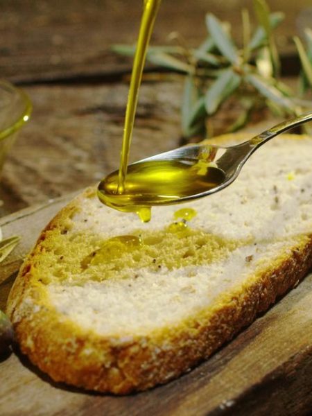 Aceite de oliva virgen extra de Arribes del Duero vertido sobre pan artesano, con aceitunas y ramas de olivo.